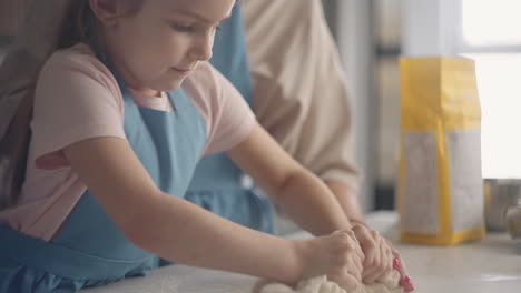 little-girl-and-her-mother-are-kneading-dough-in-home-kitchen-cooking-and-baking-domestic-bread